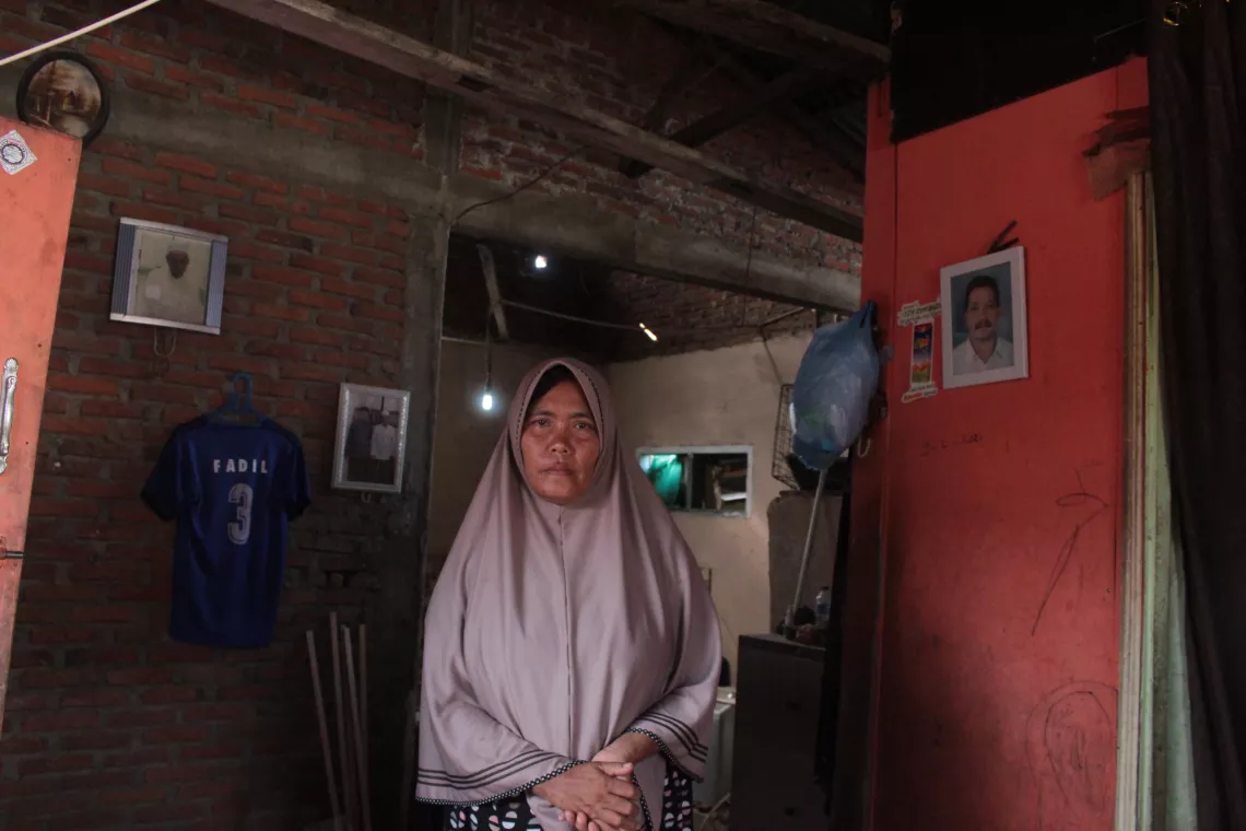 Ibu Ernawati at her home in Gampong Lamlagang district in Banda Aceh. She stands next to a photo of her late husband.